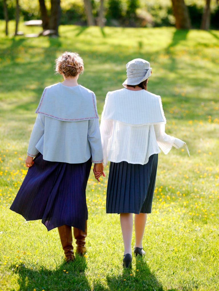 Back view of two women surrounded by greenery wearing the Metro Middy Blouse