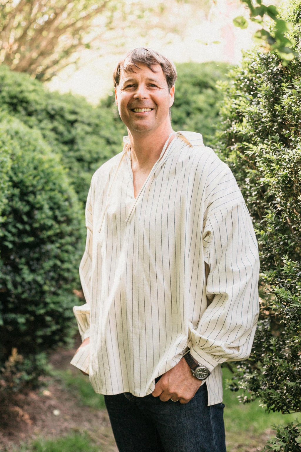 Smiling man, standing with hands in pockets,surrounded by greenery, wearing 204 Missouri River Boatman's Shirt