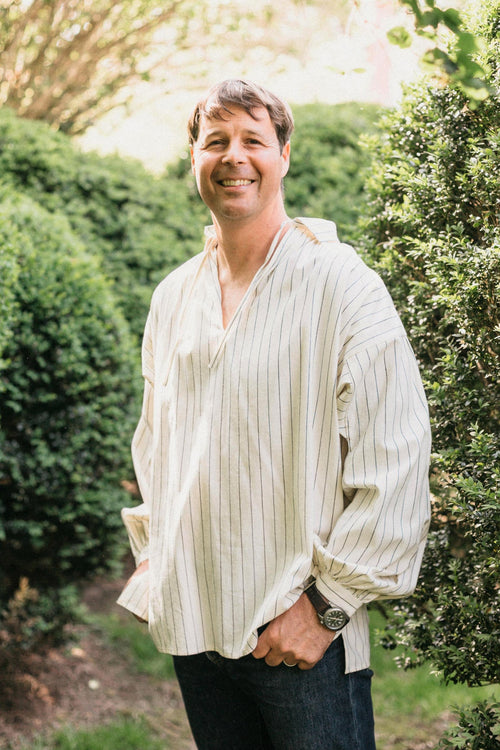 Smiling man, standing with hands in pockets,surrounded by greenery, wearing 204 Missouri River Boatman's Shirt