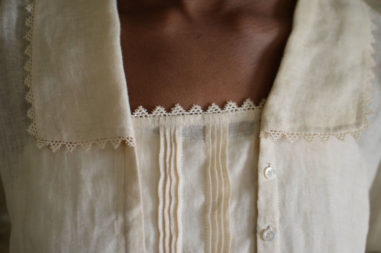 Close up of 210 Armistice Blouse long collar forming a deep rectangle, trimmed with lace at the edges of the collar worn by African woman