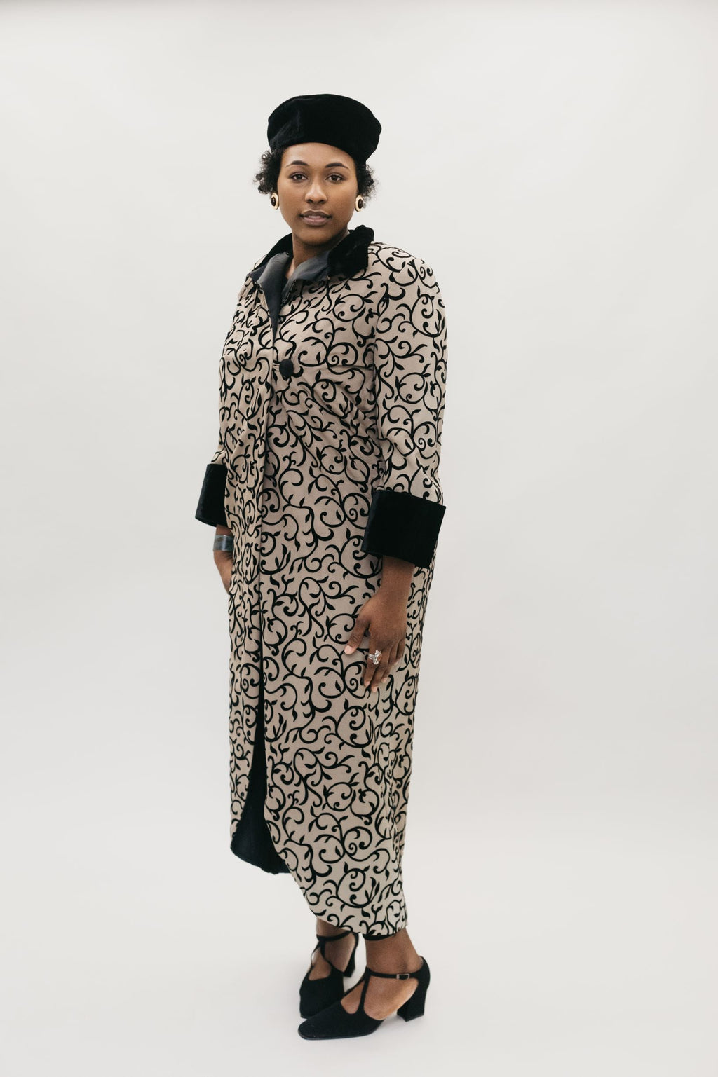 Black woman wearing brown and black coat with black cuffs and high collar.