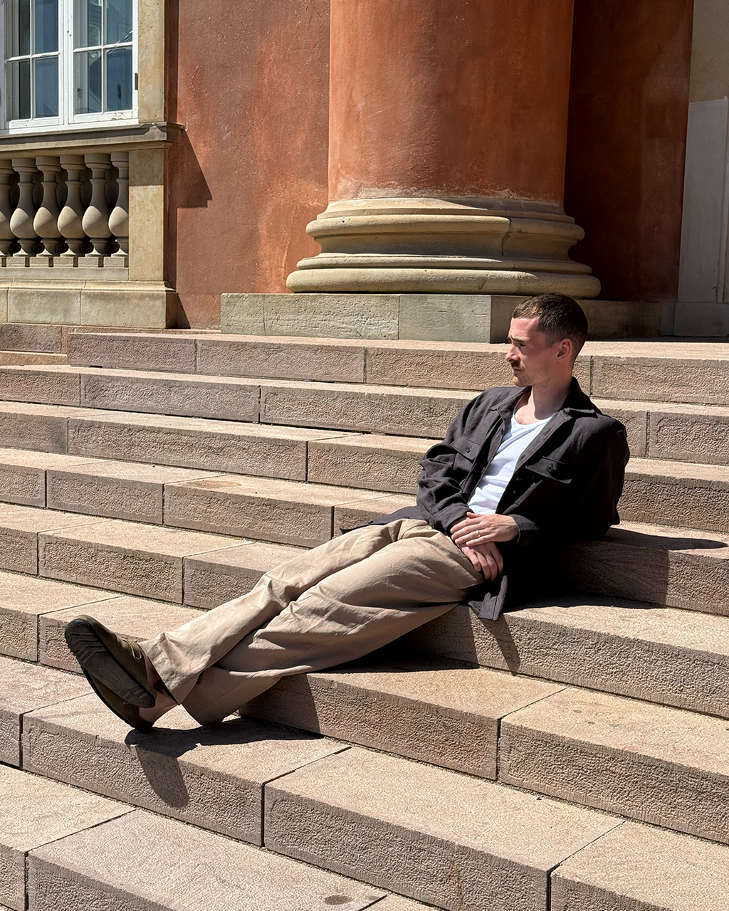 Man sitting on stone steps in front of a classical building