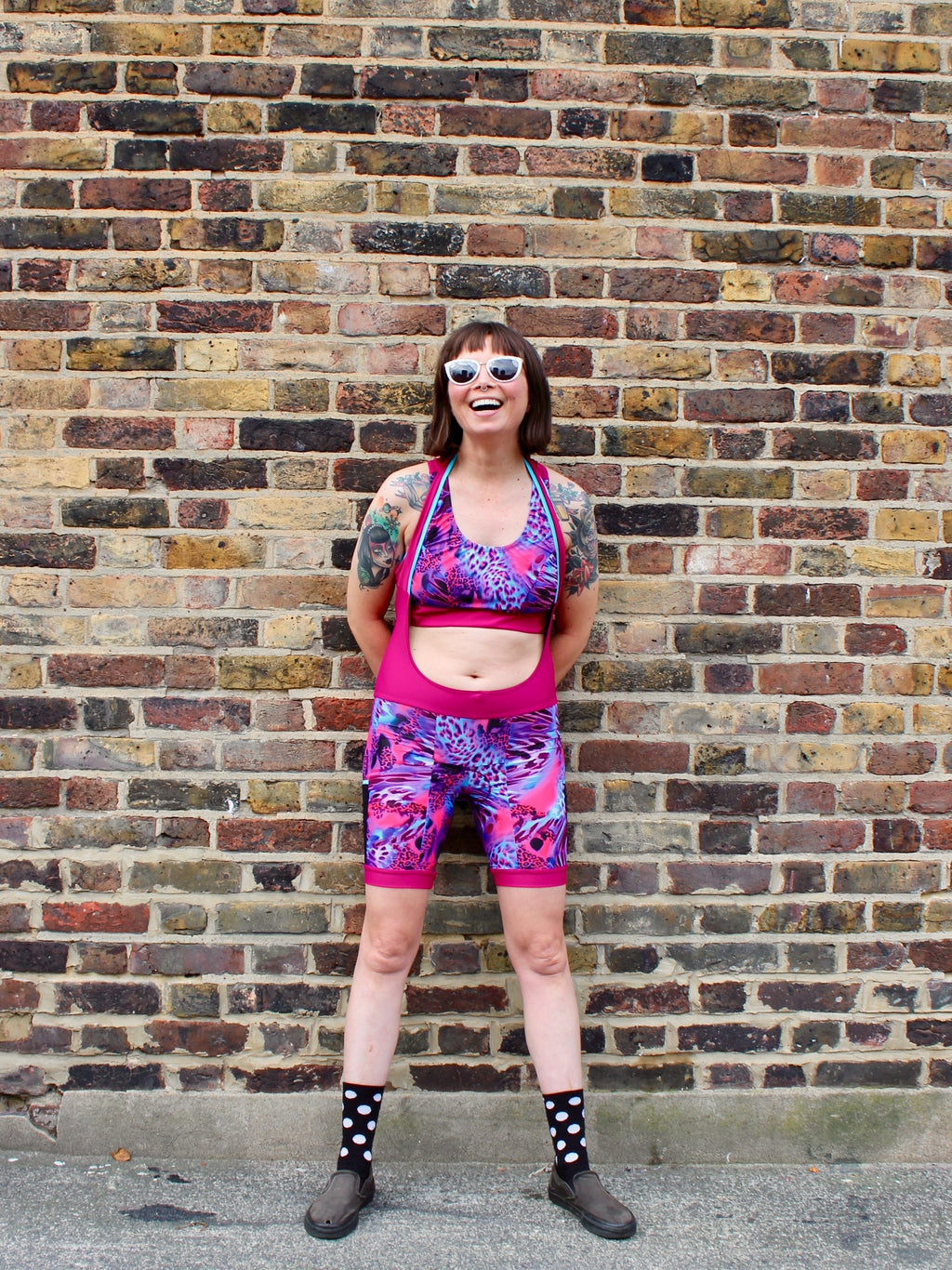 Rouleur Leggings view B - image of woman in brightly coloured bib shorts standing against a brick wall