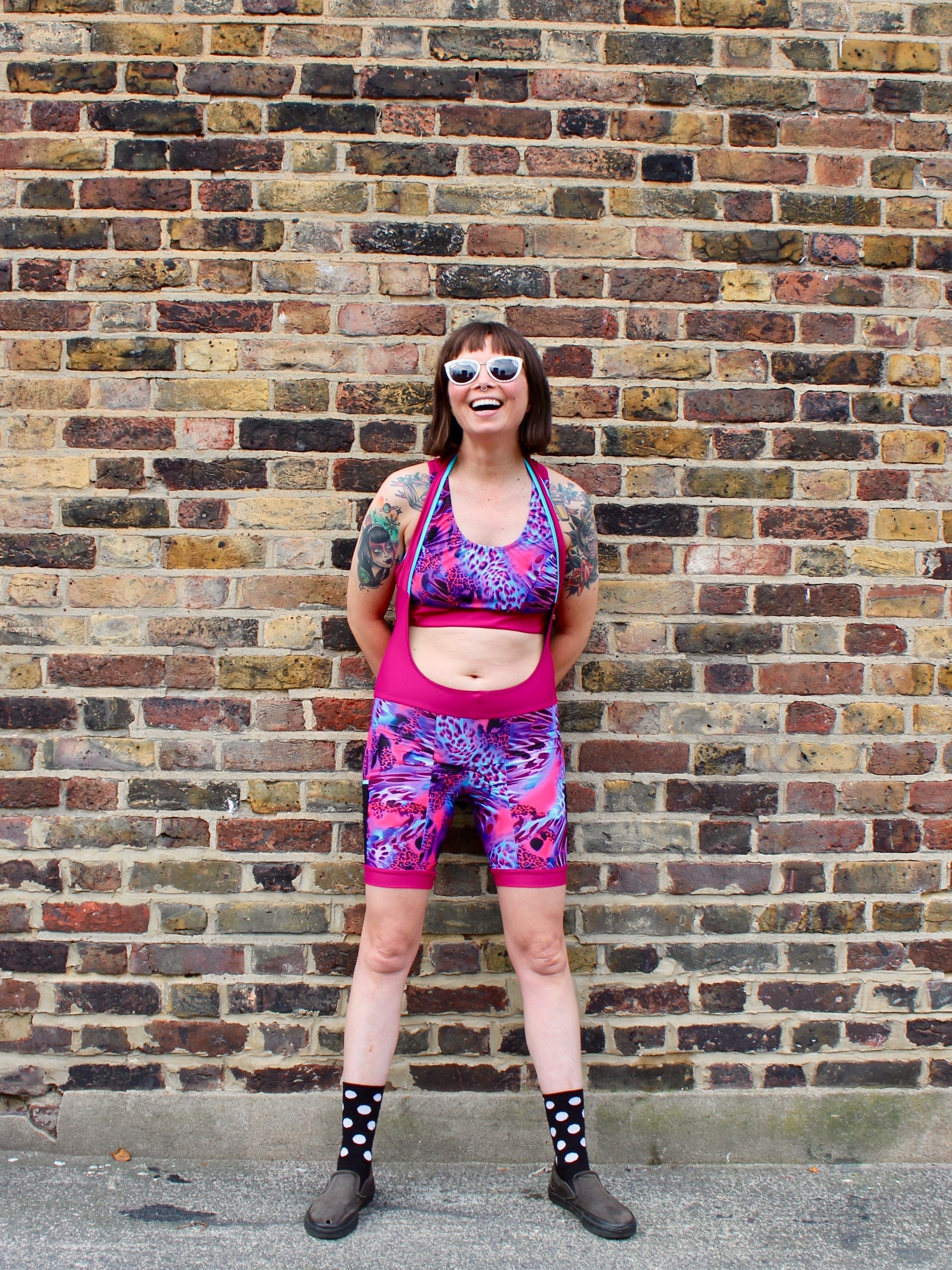 Rouleur Leggings view B - image of woman in brightly coloured bib shorts standing against a brick wall